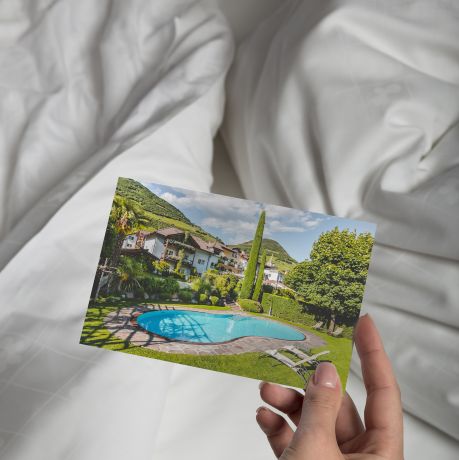 A person looking at a postcard of the pool at | Magdalener Hof | Bolzano, Italy 
