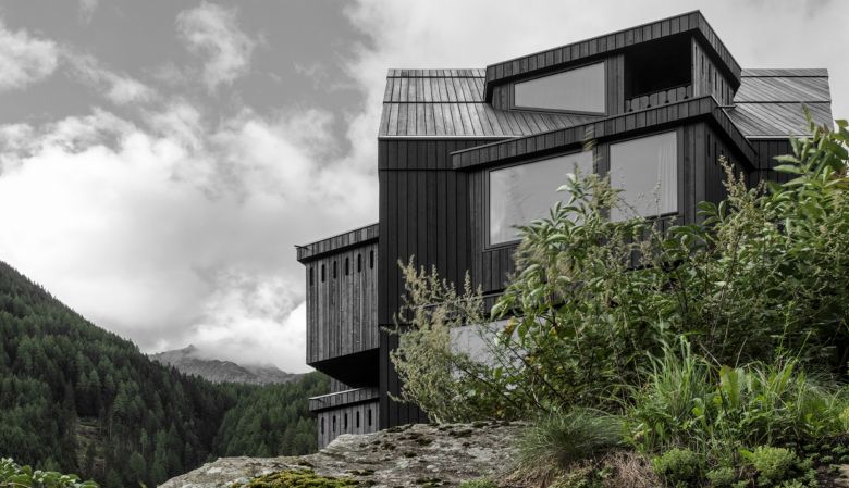 Design Hotel Bühelwirt in South Tyrol, blackened wooden facade against the lich green meadows of the alps  - striking architecture by Pedevilla,