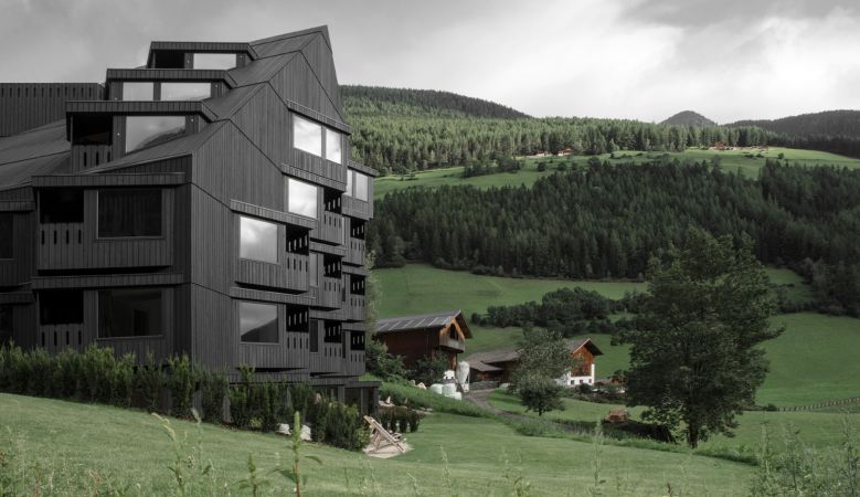 Design Hotel Bühelwirt in South Tyrol, blackened wooden facade against the lich green meadows of the alps  - striking architecture by Pedevilla,